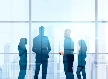 Four coworkers standing in front of a window overlooking a large city