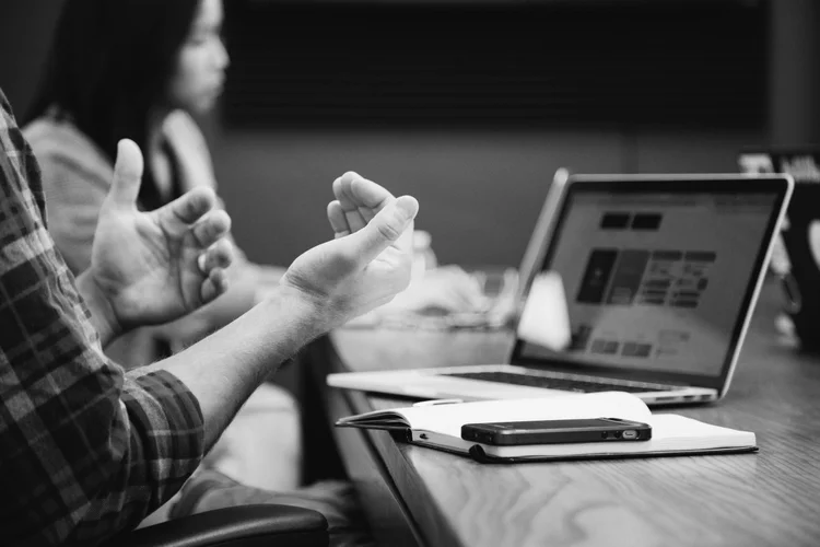 Two people sitting at a table looking at a laptop